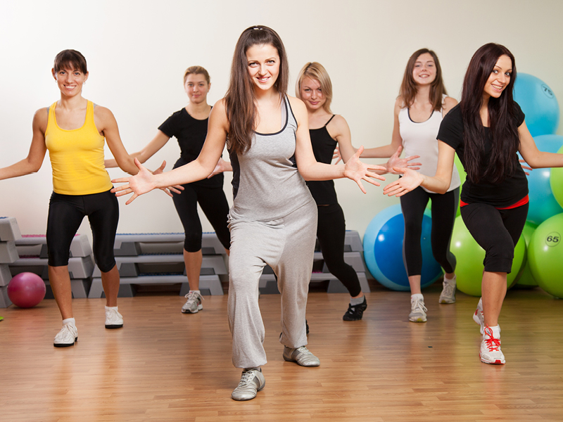 Group of happy dancers in a fitness studio participating in an energetic dance class, expressing joy and movement.